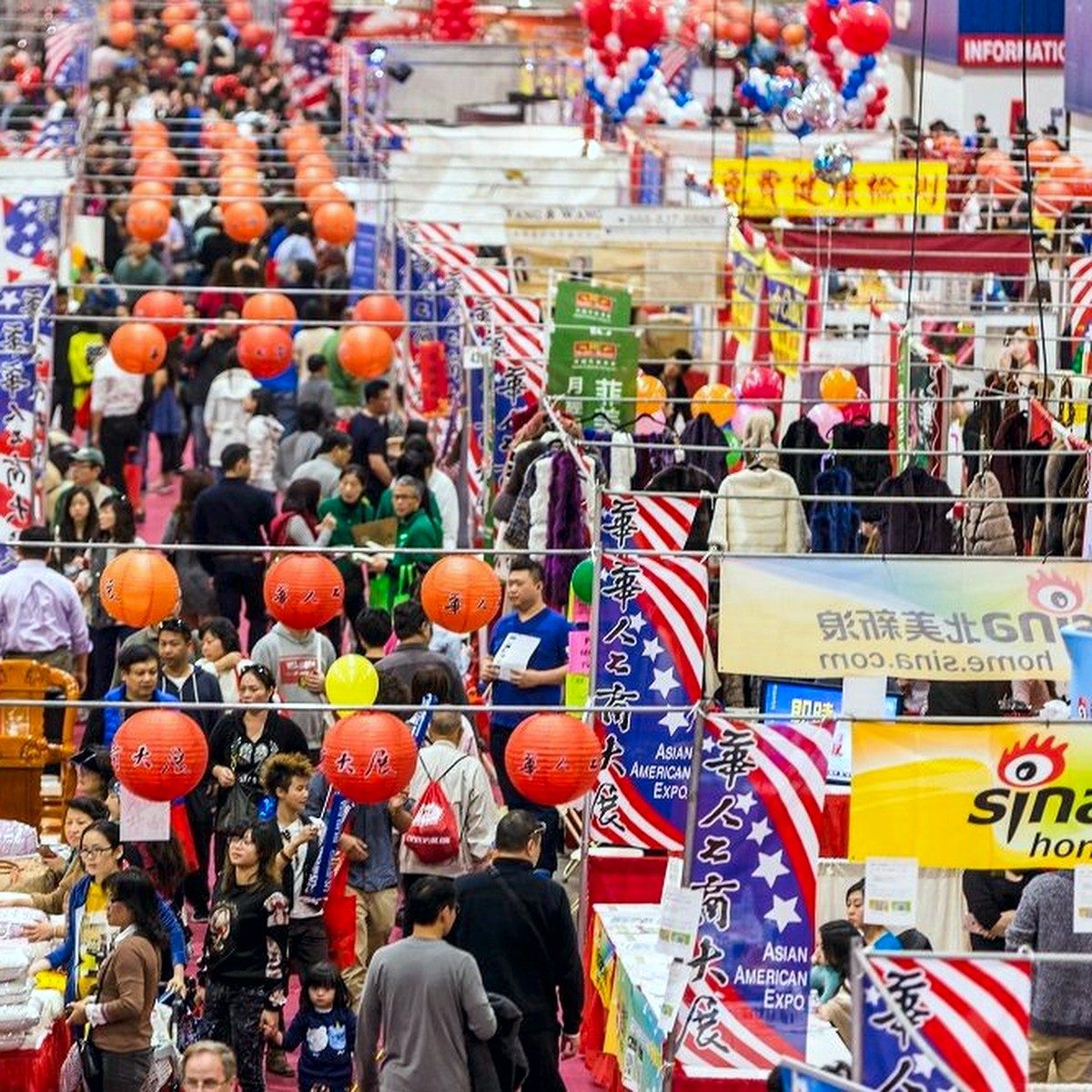 Packed exhibit hall aisle with Asian American Expo banners and red lanterns overhead